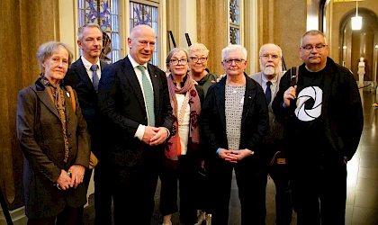 Eine Hand, die sich einem See und der sich dahinter befindenden aufgehenden Sonne entgegenstreckt, Bild in schwarz-weiß